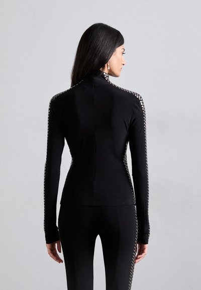Black fitted top with long sleeves, mock neck, and silver embellishments along the shoulder seams, made from a soft stretch fabric.