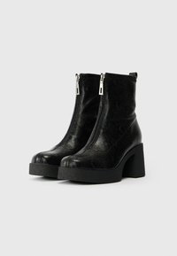 Μαύρα ankle boots με υφασμάτινη υφή, που διαθέτουν διπλές φερμουάρ, στρογγυλή μύτη και παχιές σόλες.