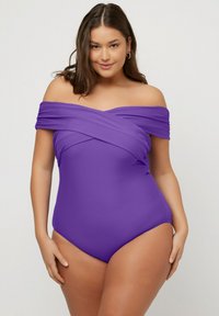 Lilla off-the-shoulder one-piece badebukser med krydsdesign, glat tekstur og højt udskårne benåbninger.