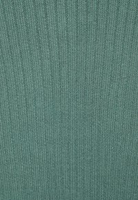 Tessuto lavorato a maglia di colore teal con una texture a righe verticali. Il materiale appare morbido con un motivo uniforme in tutto il tessuto.