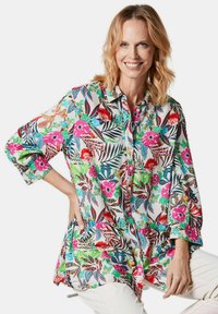 Button-up Hemd mit einem lebhaften Blumen- und Blattmuster in Pink, Blau und Grün auf weißem Hintergrund, mit langen Ärmeln und lockerer Passform.