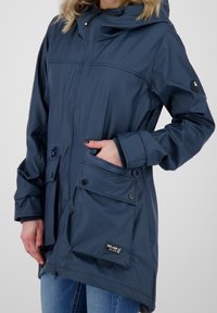 Granatowa wodoodporna parka z kapturem, zamek błyskawiczny, przednie kieszenie na zatrzaski i elastyczne mankiety. Posiada markową metkę na dolnej kieszeni.