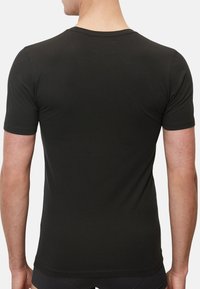 Zwart t-shirt met korte mouwen, gemaakt van zachte stof met een klassieke ronde hals. Heeft een getailleerd ontwerp en minimale naden op de rug.