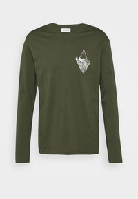 Olivenfarbene Baumwoll-T-Shirt mit langen Ärmeln und einem weißen Grafikdesign eines Eisbergs und Berges auf der linken Brust. Glatte Textur.