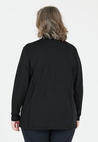 Sort langærmet skjorte med afslappet pasform, glat tekstur og enkelt design. Har en lige kant og rund halsudskæring.