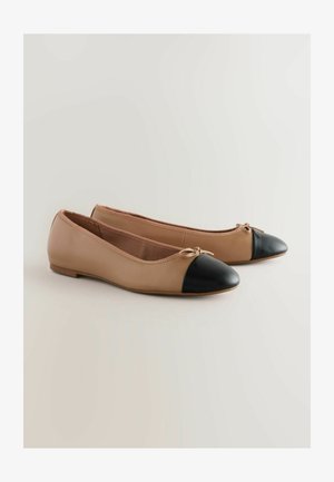 Balerīnas, kas izgatavotas no gludas bēšas ādas ar melnu noapaļotu purngalu. Iekļauj mazu loku akcentu priekšā un zemu profilu dizainu.