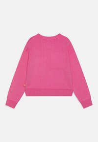 Růžový pletený svetr s kulatým výstřihem, dlouhými rukávy a zkráceným střihem. Má žebrované manžety a lem, s malou nášivkou na boku.