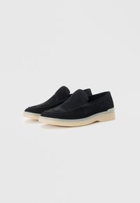 Sorte semskede loafers med en glatt finish, med en lys gummisåle og et minimalistisk design. Ingen snøring eller maskindeler synlige.