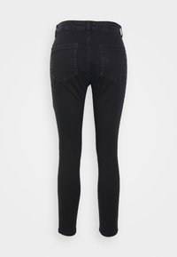 Jeans pretos de corte slim com cinco bolsos, detalhes cosidos e um ligeiro elastano para conforto. Textura de denim suave com um acabamento limpo.