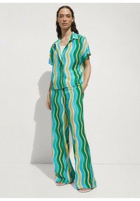 Dvoudílný outfit skládající se z košile s krátkým rukávem a kalhot se širokými nohavicemi. Vyrobeno z lehkého materiálu s vlnitými pruhy v zelené, modré, žluté a oranžové barvě.