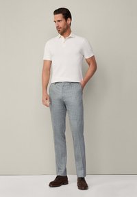 Lichtbeige polo met korte mouwen, gecombineerd met lichtgrijze taillepantalon en bruine suède schoenen. Eenvoudig ontwerp met een klassieke pasvorm.