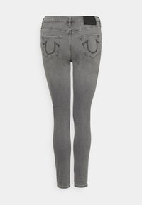 Jeans ajustados grises con una textura suave, que presentan costuras en contraste y bolsillos traseros decorativos con adornos de marca.