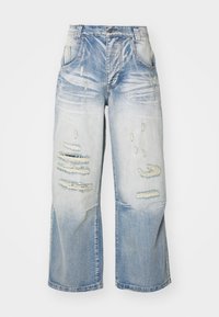 Ljust blå vida jeans med en blekt tvätt och slitna lappar på framsidan av låren och knäna.