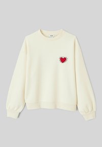Sweatshirt couleur crème avec un col rond, des épaules tombantes et des manches bouffantes ; présente une broderie en forme de cœur rouge sur la poitrine.