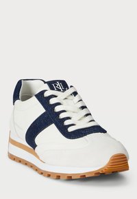 Bílé tenisky s námořnickými denimovými akcenty, texturovanými koženými panely a bílými tkaničkami. Mají světlou hnědou gumovou podrážku s rýhovaným vzorem.