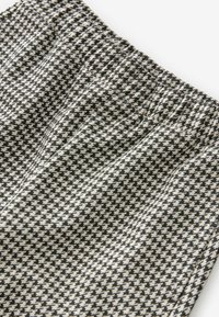 Mustekko, jossa on musta-valkoinen houndstooth-kuvio, joustava vyötärö. Pehmeä tekstuuri, tasaiset saumat ja kevyt muotoilu.