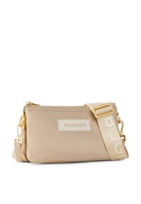 Borsa beige con accessori dorati, chiusura a zip e patch con logo. Presenta una tracolla removibile con nome del marchio in rilievo. Realizzata in materiale liscio.