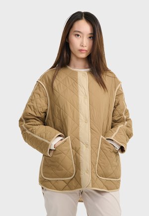 Veste matelassée beige avec un devant à boutons-pression, un bord contrastant beige clair, de grandes poches lat�érales et une coupe décontractée. Tissu texturé avec des coutures visibles.