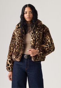 Faux fur jasje met een luipaardprint, met een hoge kraag, ritssluiting en lange mouwen. Gecombineerd met donkere denim broeken.