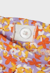 Floral-patterned fabric with purple, yellow, and orange flowers. Features a white fastening tab with a clear button and visible stitching.