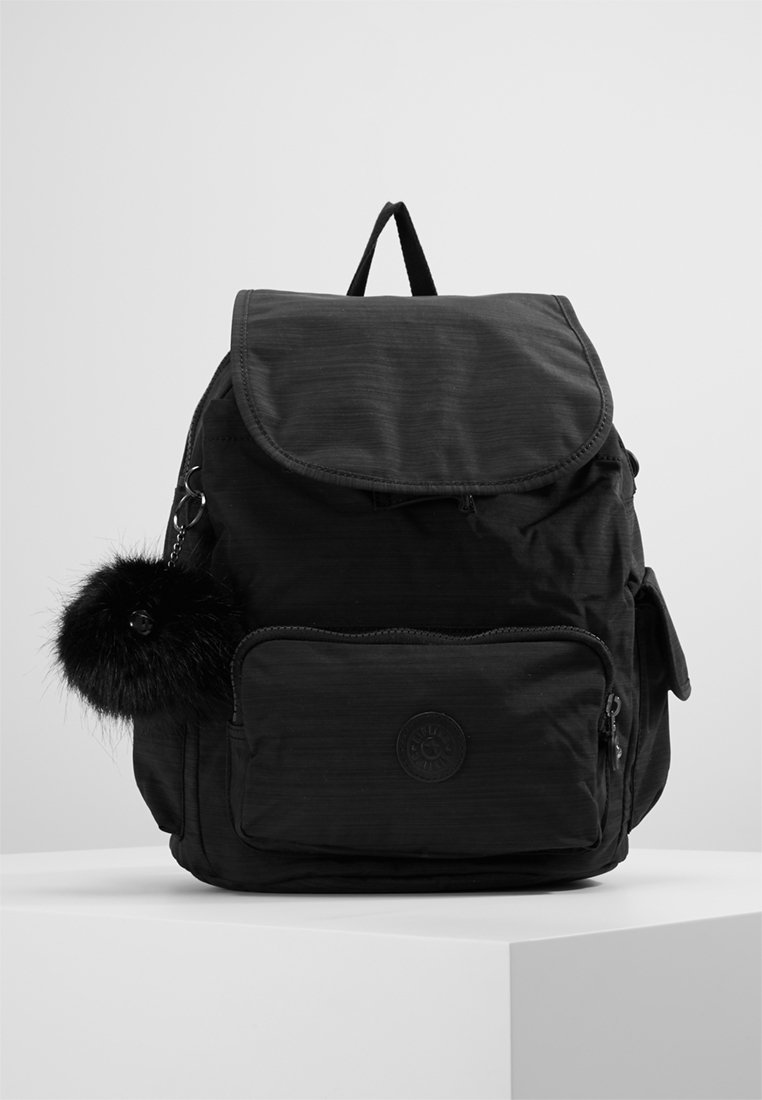 Sac à dos noir en tissu texturé, avec un rabat supérieur arrondi, une poche zippée à l'avant, des poches latérales et un pompon en fausse fourrure noire amovible.