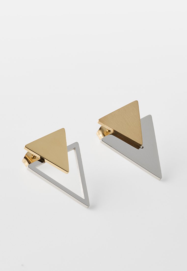 Geometrische Ohrringe mit zwei Dreiecken; eines aus vergoldetem Metall und eines aus silberfarbenem Metall mit einem ausgeschnittenen Design, versehen mit einer polierten Oberfläche.