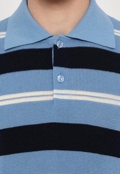 Lyseblå polo skjorte med marineblå og hvite horisontale striper. Teksturert stoff, spiss krage og detalj med to-knappers lukking.