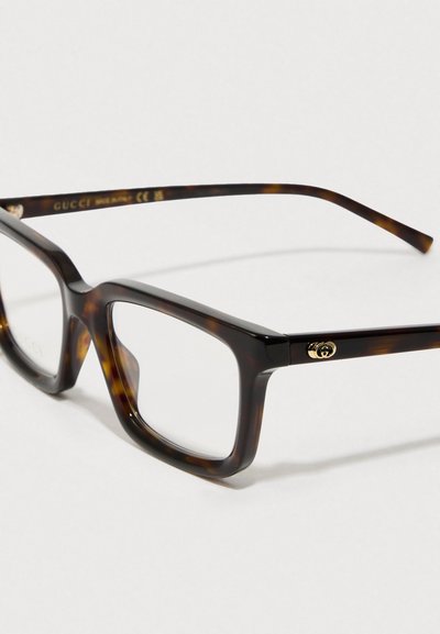 Gafas rectangulares de carey marrón con montura de plástico grueso. Acento de logo en dorado en la patilla. Lentes transparentes.