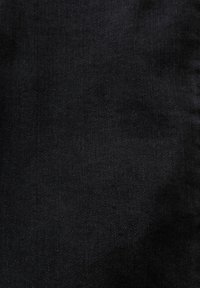 Primer plano de la textura de tela de mezclilla negra con patrón de tejido diagonal visible y sutiles variaciones de sombreado.