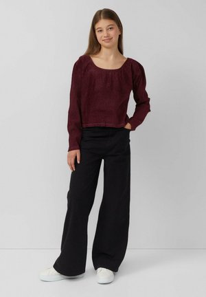 Burgunderfarbener, gerippter Langarm-Top mit quadratischem Ausschnitt, kombiniert mit schwarzen, weit geschnittenen Hosen und weißen Sneakers. Glatte Textur und lässige Passform.