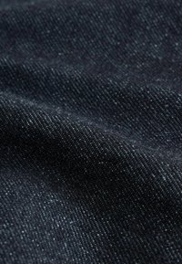 Dunkelblauer Denim-Stoff mit einer weichen Textur, der feine, subtile Muster und eine glatte, leicht verblasste Oberfläche aufweist.