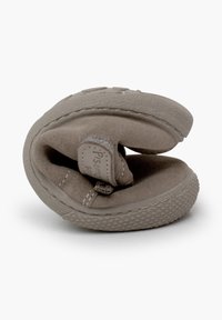 Pantofole grigie in suede con suola di gomma, piegate a metà. Presentano dettagli cuciti e un piccolo etichetta con il nome del brand all'interno.