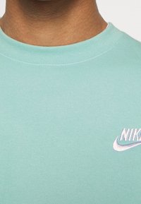 Felpa crewneck in cotone verde menta con colletto a costine e logo Nike bianco ricamato sul petto. Texture morbida, vestibilità casual.