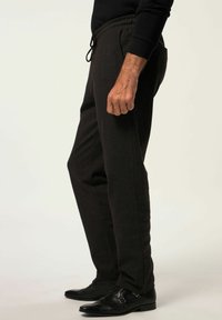 Pantalones negros texturizados con una cintura elástica y cordón ajustable. Cuenta con bolsillos laterales, diseño ajustado y se combina con zapatos negros.