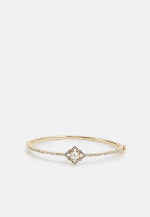 Bracelet jonc ton or avec petites pierres claires et un design central présentant une perle blanche ronde entourée d'un cadre en forme de losange serti de pierres.