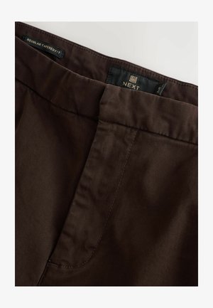 Braune schmal geschnittene Hose aus glattem Material mit einer gesteppten Taille und seitlichen Taschen. Markenlabel innen sichtbar.