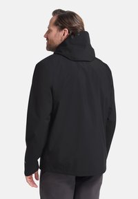 Schwarze wasserdichte Jacke mit Kapuze, die eine glatte Textur, einen lockeren Schnitt und ein einfaches Design aufweist, sichtbare Nähte und verstellbare Manschetten hat.