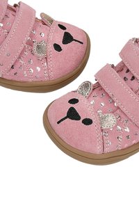 Scarpe per bambini in suede rosa, con due cinturini in Velcro, caratterizzate da un design con faccia di orsetto, dettagli metallici e piccoli fori a forma di cuore sui lati.