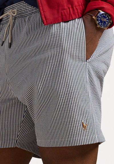 Striped shorts in blue and white, featuring an elastic waistband with drawstring, side pockets, and a small embroidered logo near the hem.