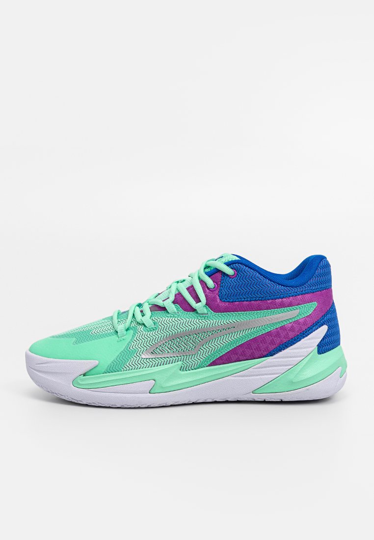 Zapatilla deportiva multicolor con parte superior en verde menta, acentos azules, detalles morados y un patrón texturizado, todo sobre una suela blanca.