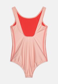 Fato de banho de uma peça em rosa suave com um interior vermelho contrastante. Apresenta alças largas, decote arredondado e uma silhueta ajustada.