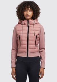 Helle rosa Pufferjacke mit Kapuze, ausgestattet mit schwarzen Reißverschlüssen, gerippten Bündchen und zwei mit Reißverschluss versehenen Vorderaschen. Glatte Textur an den Ärmeln.