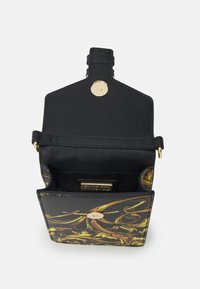 Czarna torebka z kwiatowym wzorem w złocie i zieleni, z zapięciem na magnes i wewnętrzną kieszenią. Zbudowana w eleganckim stylu.