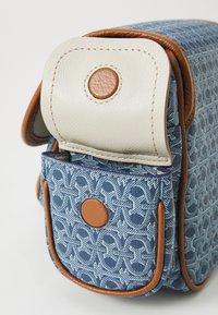 Borsa in tessuto blu a motivo con una patta in pelle beige, accenti marroni e un bottone circolare. Forma compatta e rettangolare con una tasca anteriore.
