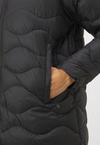 Čierna puff jacket s prešívaným vzorom, so zipsom vpredu a bočnými vreckami. Tkanina má hladkú textúru a ľahký vzhľad.