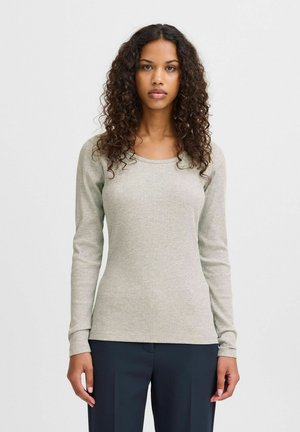 Maglietta a maniche lunghe in tessuto grigio chiaro a coste con scollatura arrotondata, forma aderente e texture liscia. Abbinata a pantaloni scuri.