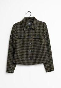 Lyhennettäjä tummanvihreästä ja mustasta houndstooth-kuosista, perinteisellä kauluksella, etupusseilla ja mustilla nappeilla. Yksityiskohdat ovat teksturoituja.