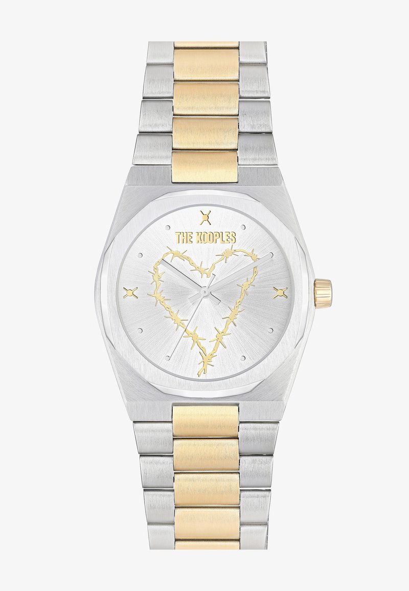 Klocka i rostfritt stål med detaljer i gult guld. Oktagonalt hölje, silverfärgad urtavla med ett hjärtdesign i guld. Länkarmband.