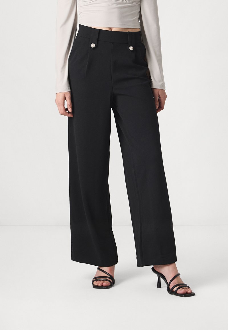 Pantalons larges noirs à taille haute, dotés de deux boutons décoratifs et de plis subtils. Fabriqués dans un tissu lisse et léger.
