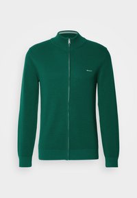 Pull zippé vert foncé en maille texturée, avec poignets, col et bas côtelés, avec un petit logo GANT sur la poitrine gauche.